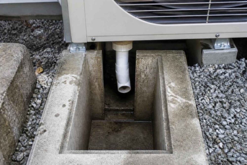 Betonowy odpływ skroplin pod jednostką klimatyzacyjną na żwirowym podłożu